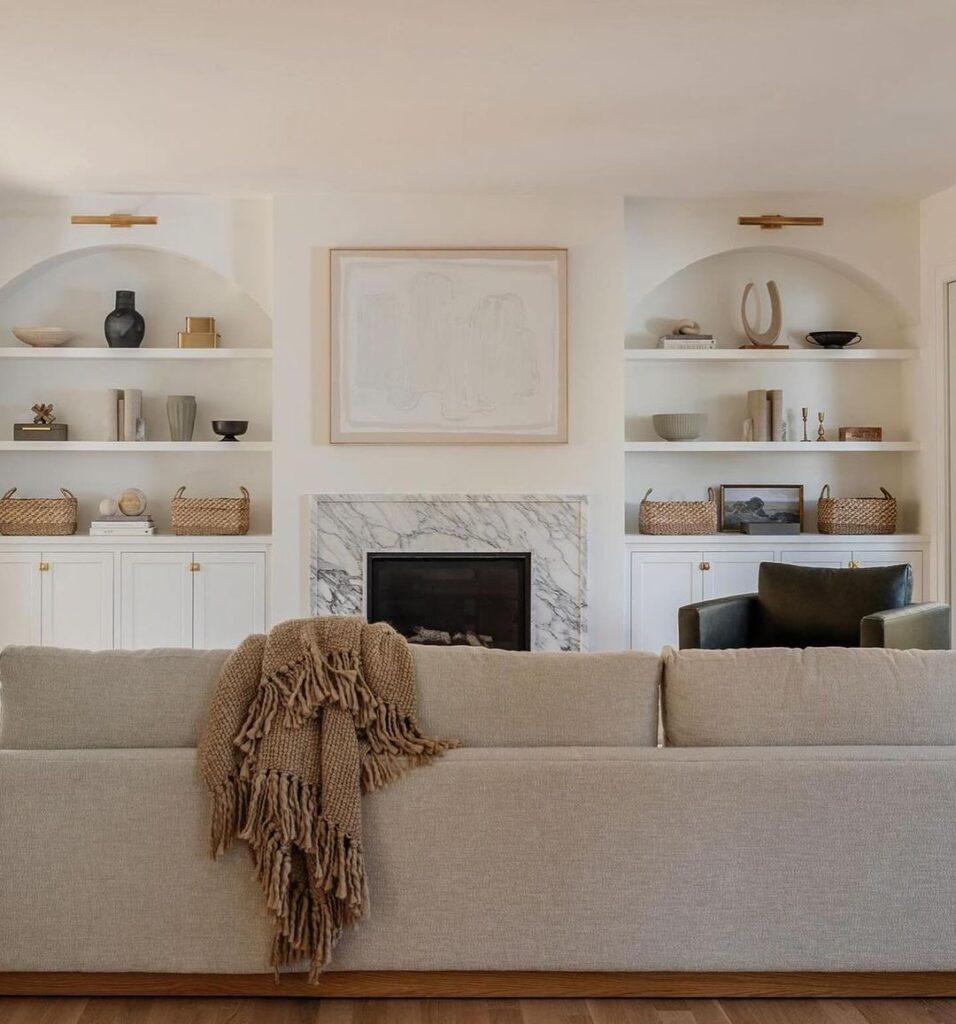 Neutral living room with built-in shelves and marble fireplace