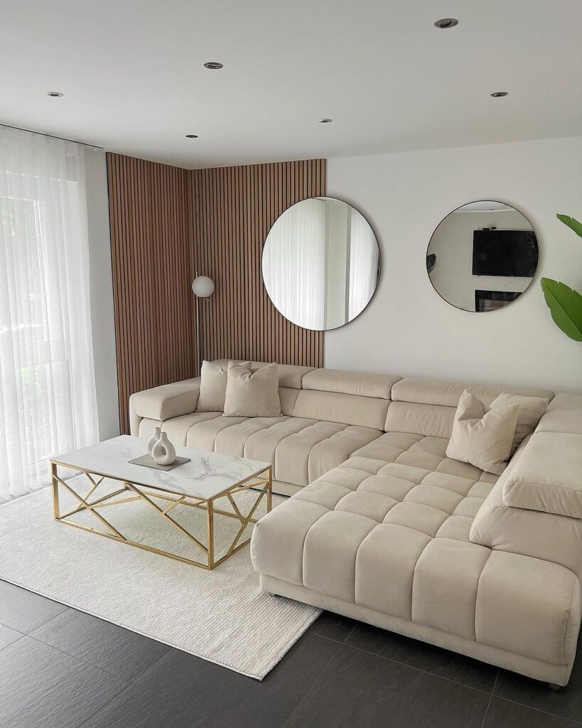 Modern living room with large beige sofa and round mirrors.