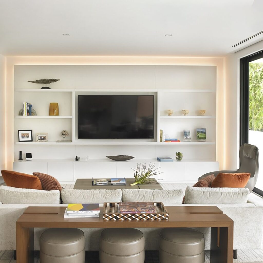 Modern living room with illuminated media wall and comfortable seating arrangement.