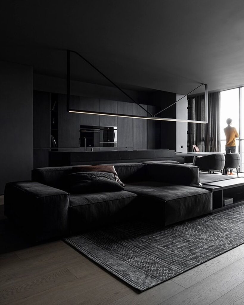 Minimalist black living room with geometric lighting and floor-to-ceiling windows.