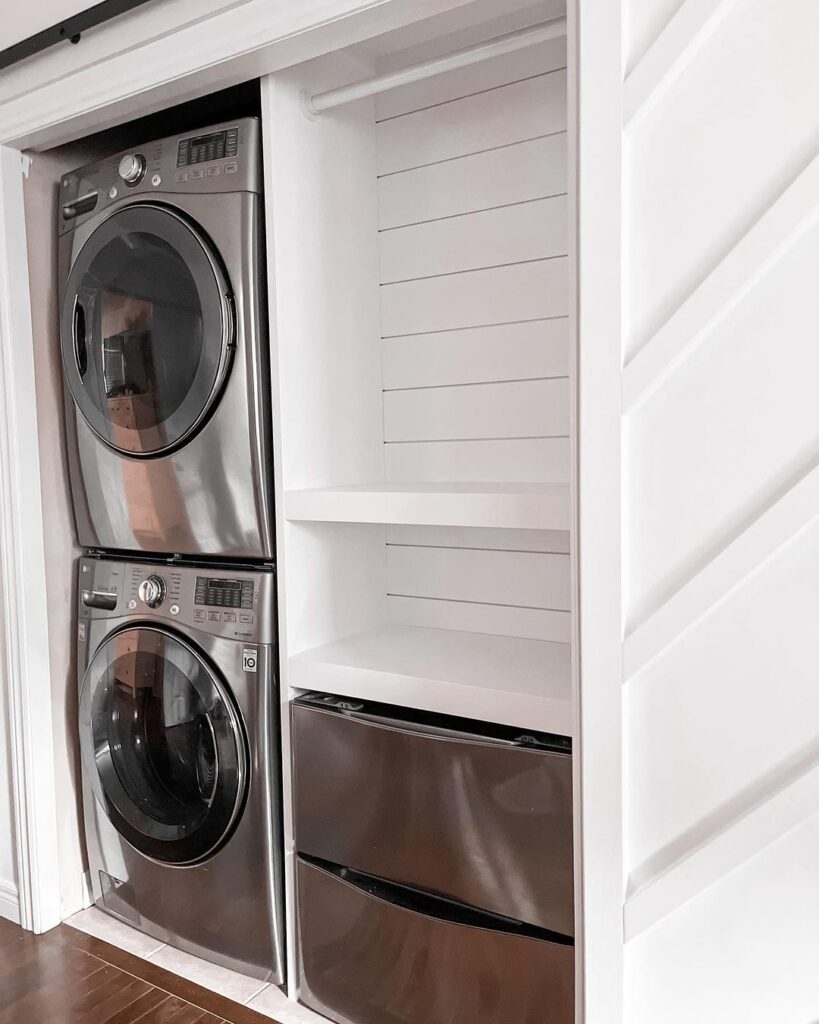 Stacked washer and dryer in white shiplap closet.