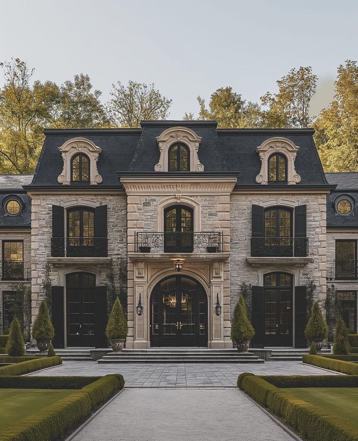 "Symmetrical stone mansion with black trim and formal gardens"