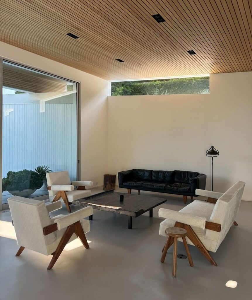 Minimalist living room with wooden ceiling and large windows.