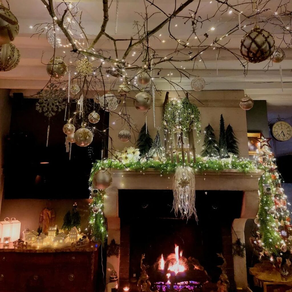 Enchanted fireplace display with hanging ornaments from natural branches and lit garland