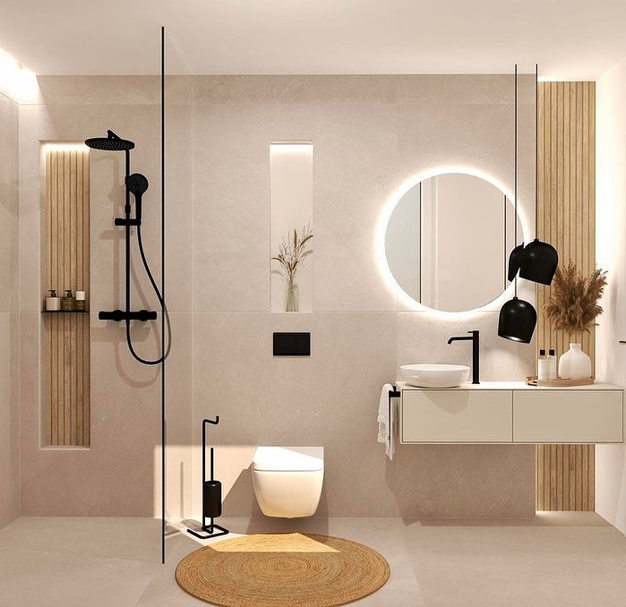 Modern beige bathroom with black fixtures and circular mirror.