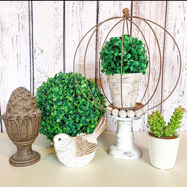 Farmhouse style decor arrangement with boxwood spheres white bird and metal orb holder