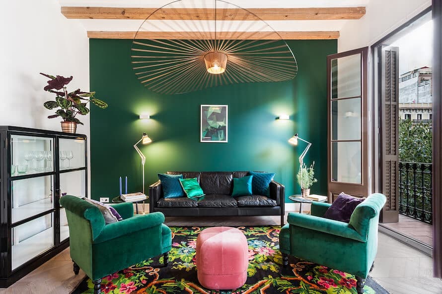 Emerald green living room with velvet chairs black sofa and sunburst chandelier