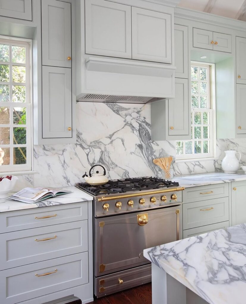  White kitchen with marble backsplash and brass accented range