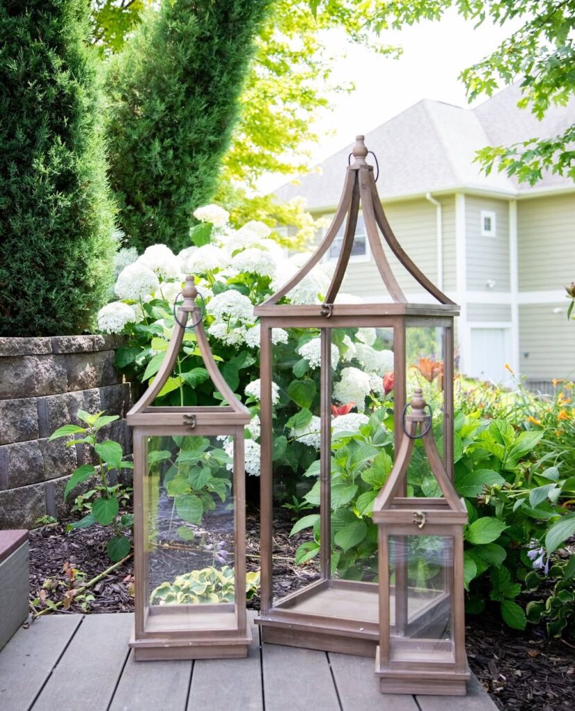 Three bronze lanterns arranged on deck with white hydrangeas and greenery