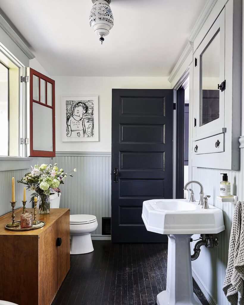 Farmhouse bathroom with navy door and pedestal sink