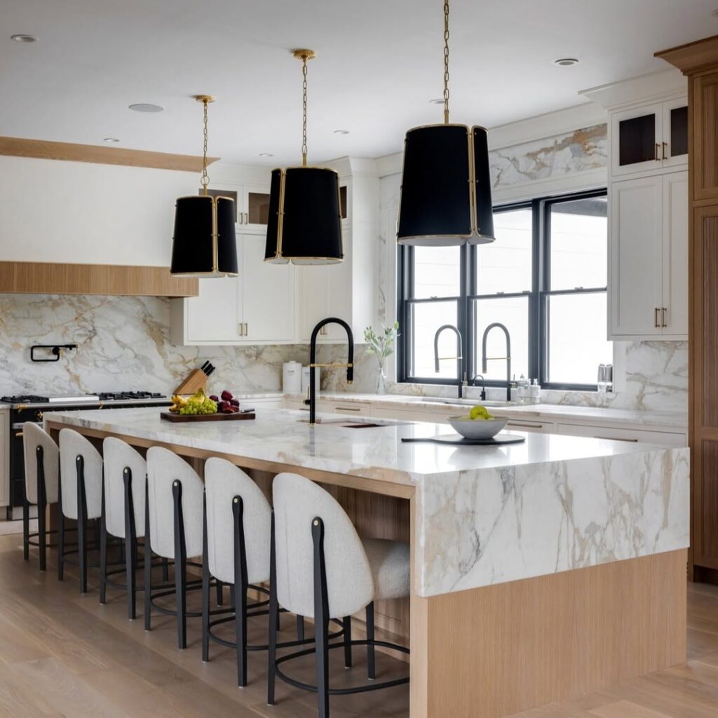 Elegant white kitchen with black pendant lights, marble island, and built-in appliances