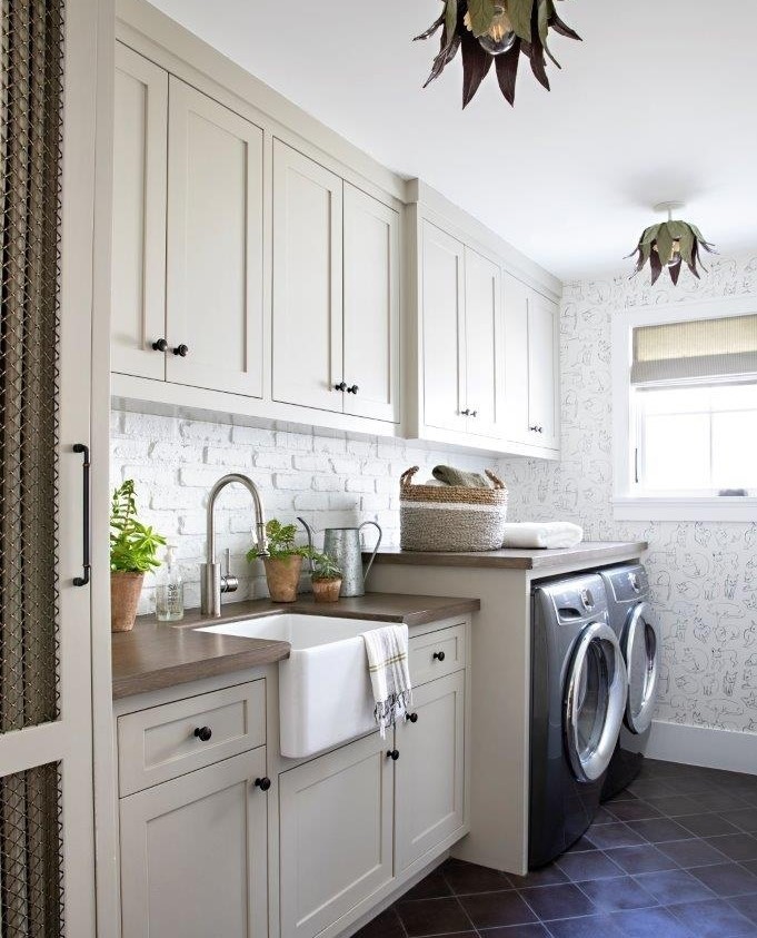 White laundry room with farmhouse sink botanical wallpaper and dark tile flooring