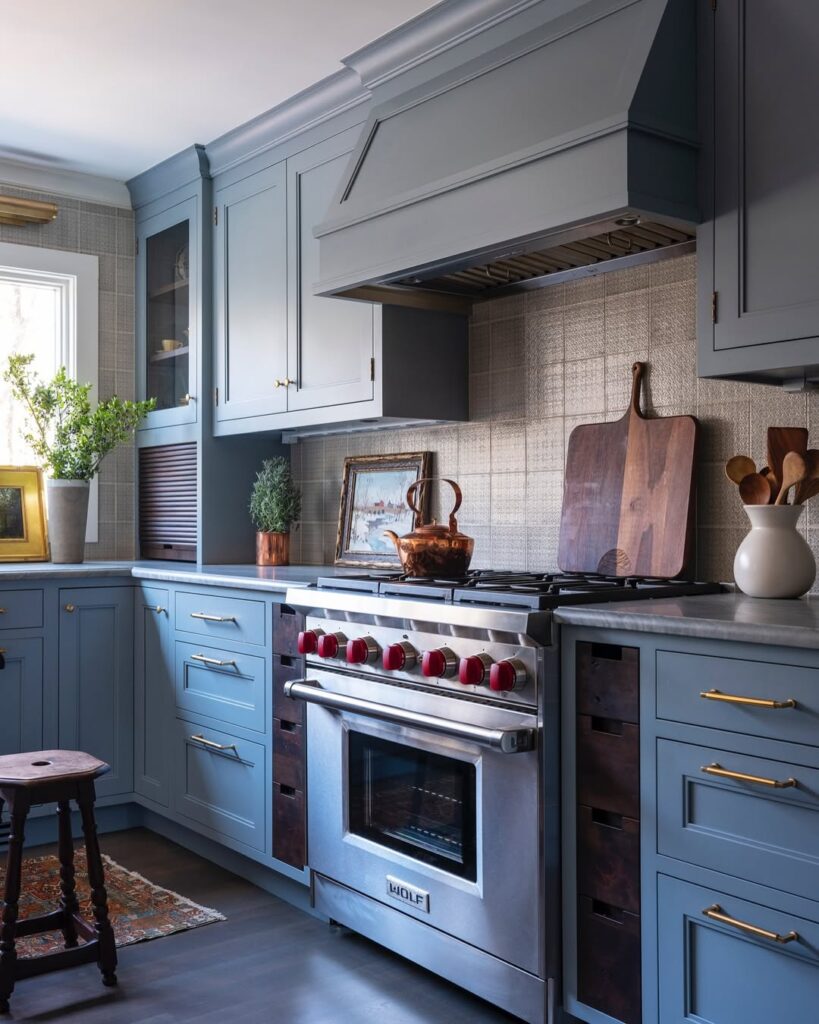 Blue kitchen with Wolf range brass handles and textured backsplash