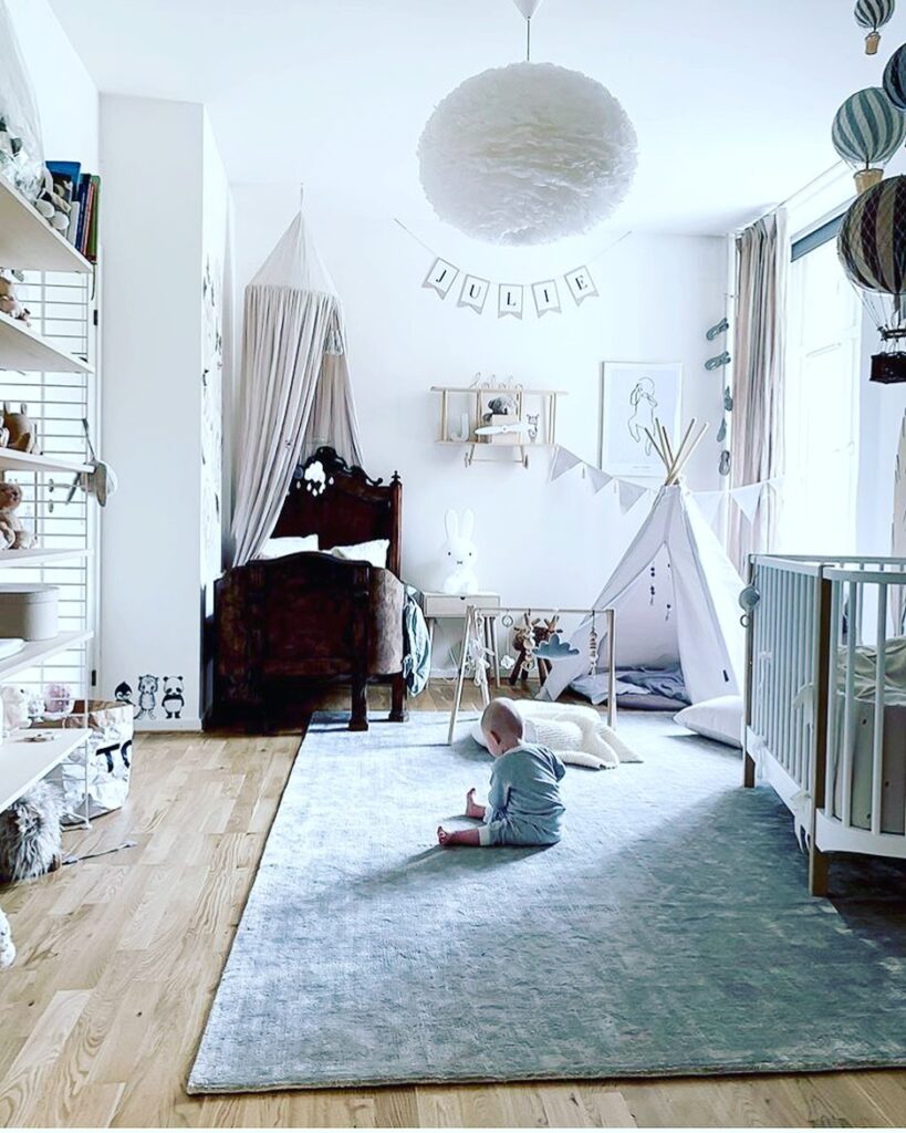 Nursery with vintage bed antique canopy and white teepee featuring name banner and balloon decor