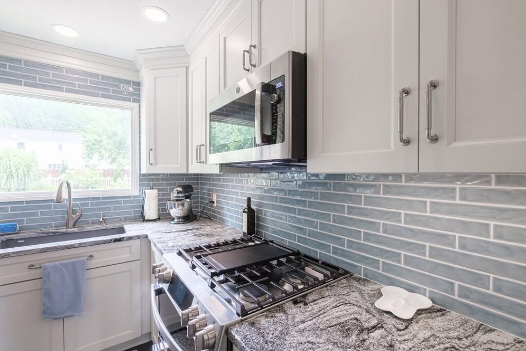 White kitchen with blue subway tile backsplash and granite countertops