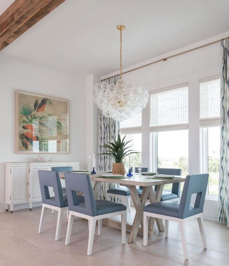 Coastal dining room with bubble chandelier blue chairs and tropical artwork