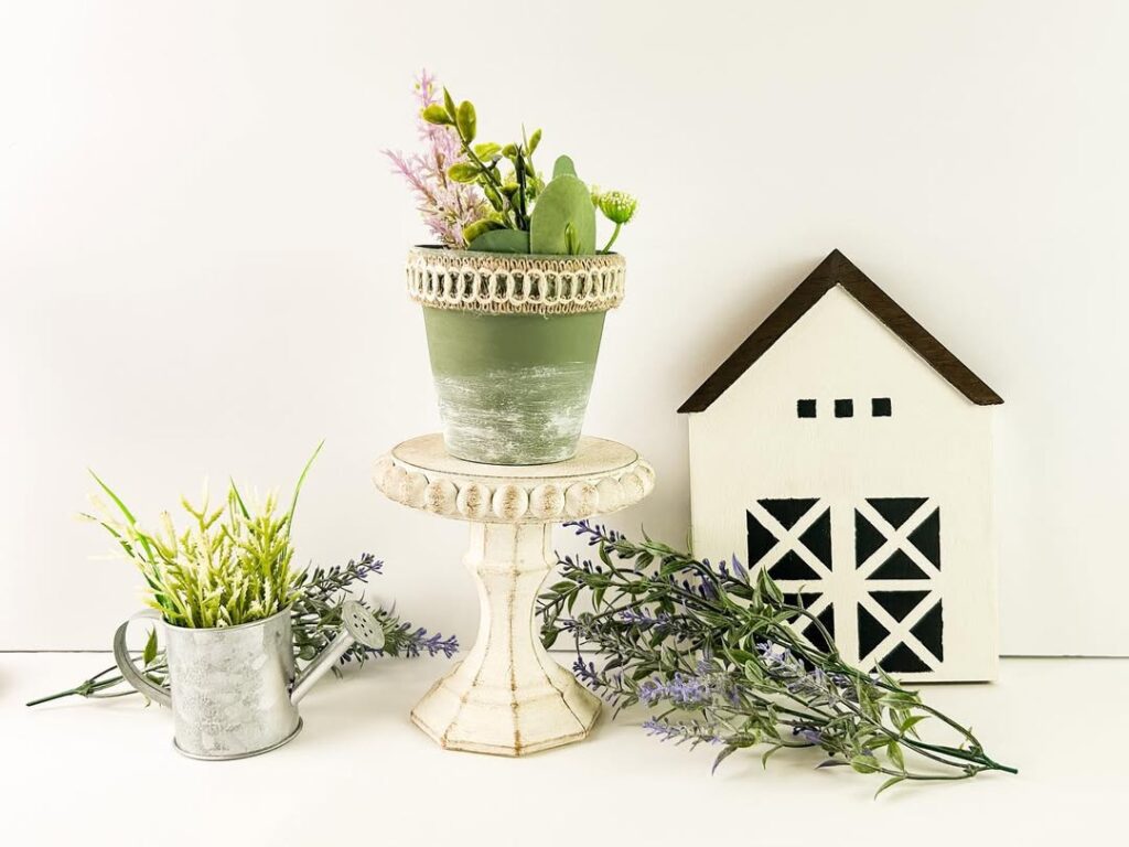 White pedestal with green potted plant and decorative farmhouse elements