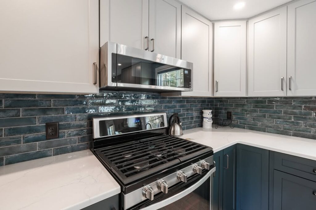 Two tone kitchen with white and navy cabinets and blue tile backsplash