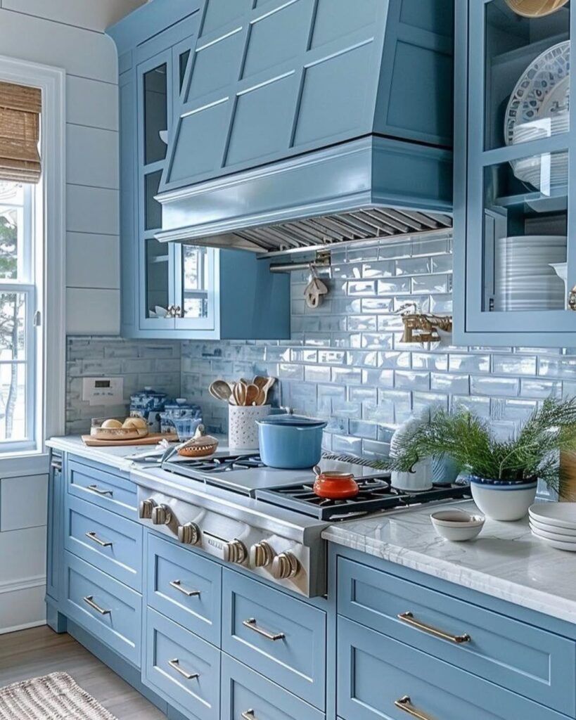 Blue kitchen with custom range hood white tile backsplash and marble counters