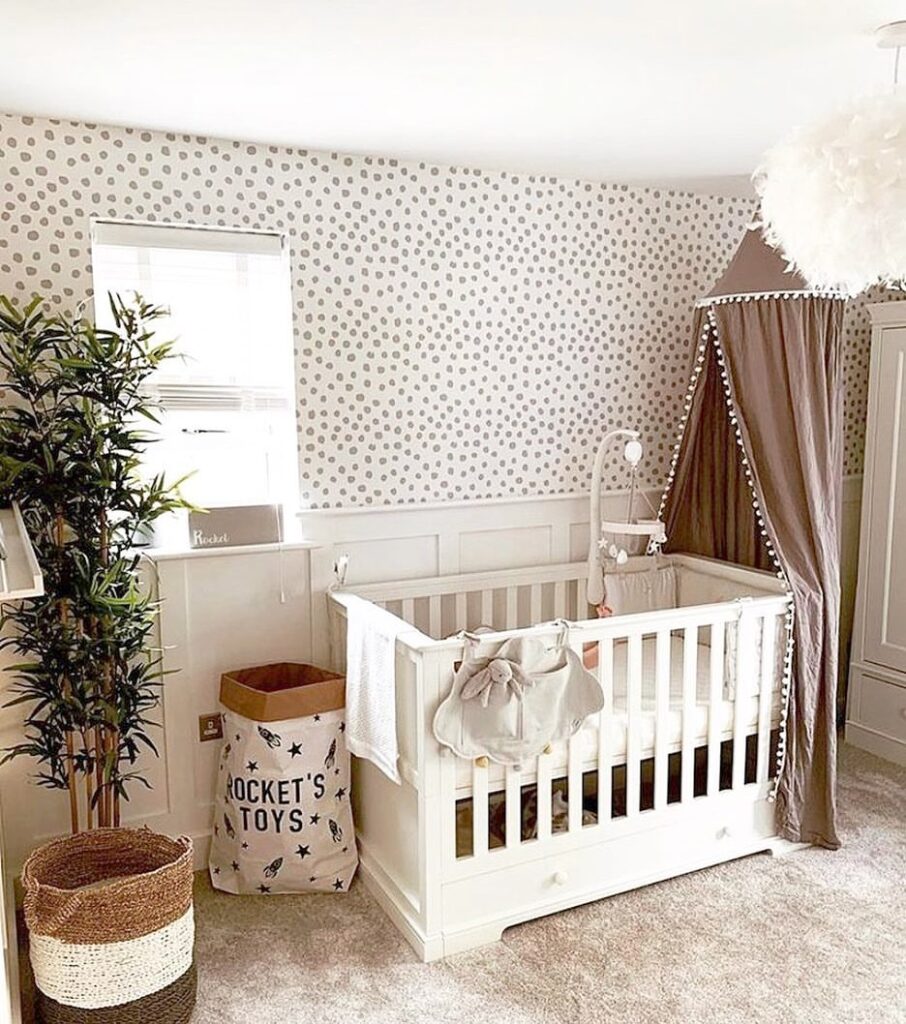 Neutral nursery with spotted wallpaper white crib bamboo plant and woven storage baskets