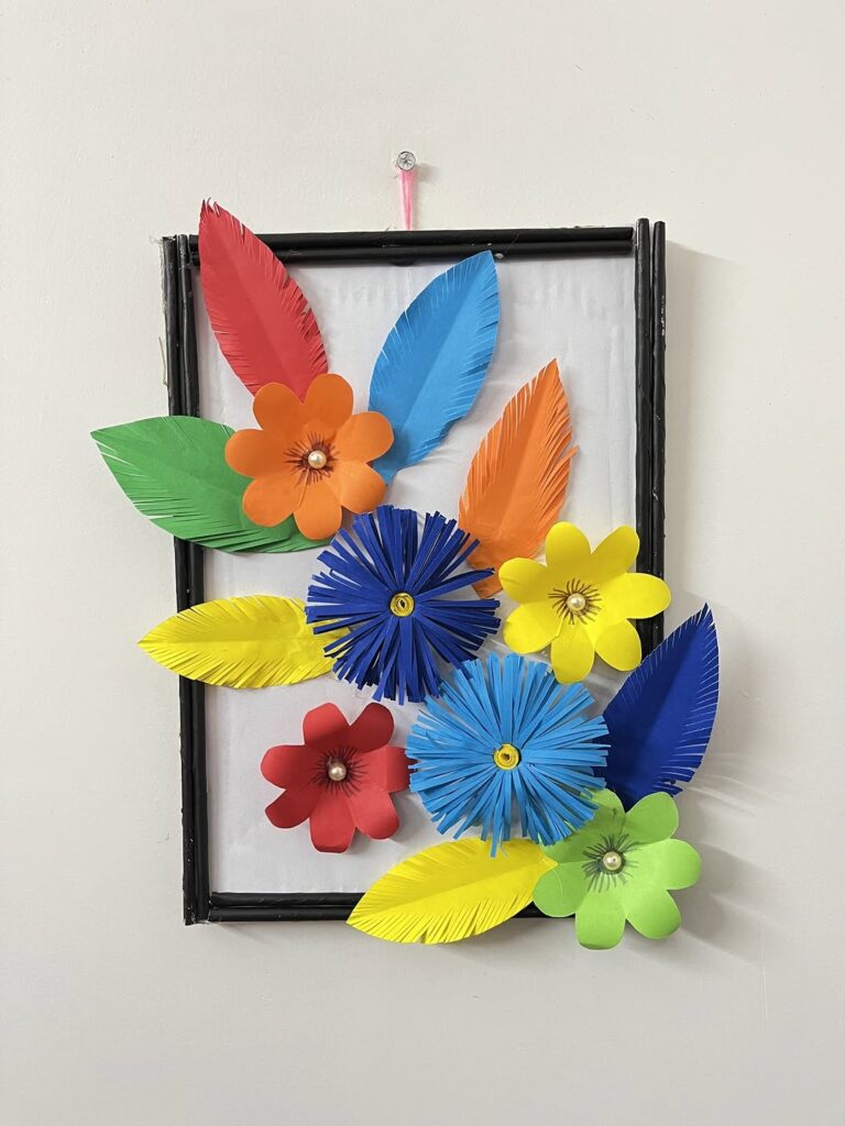 Framed colorful paper flowers and feathers in artistic arrangement