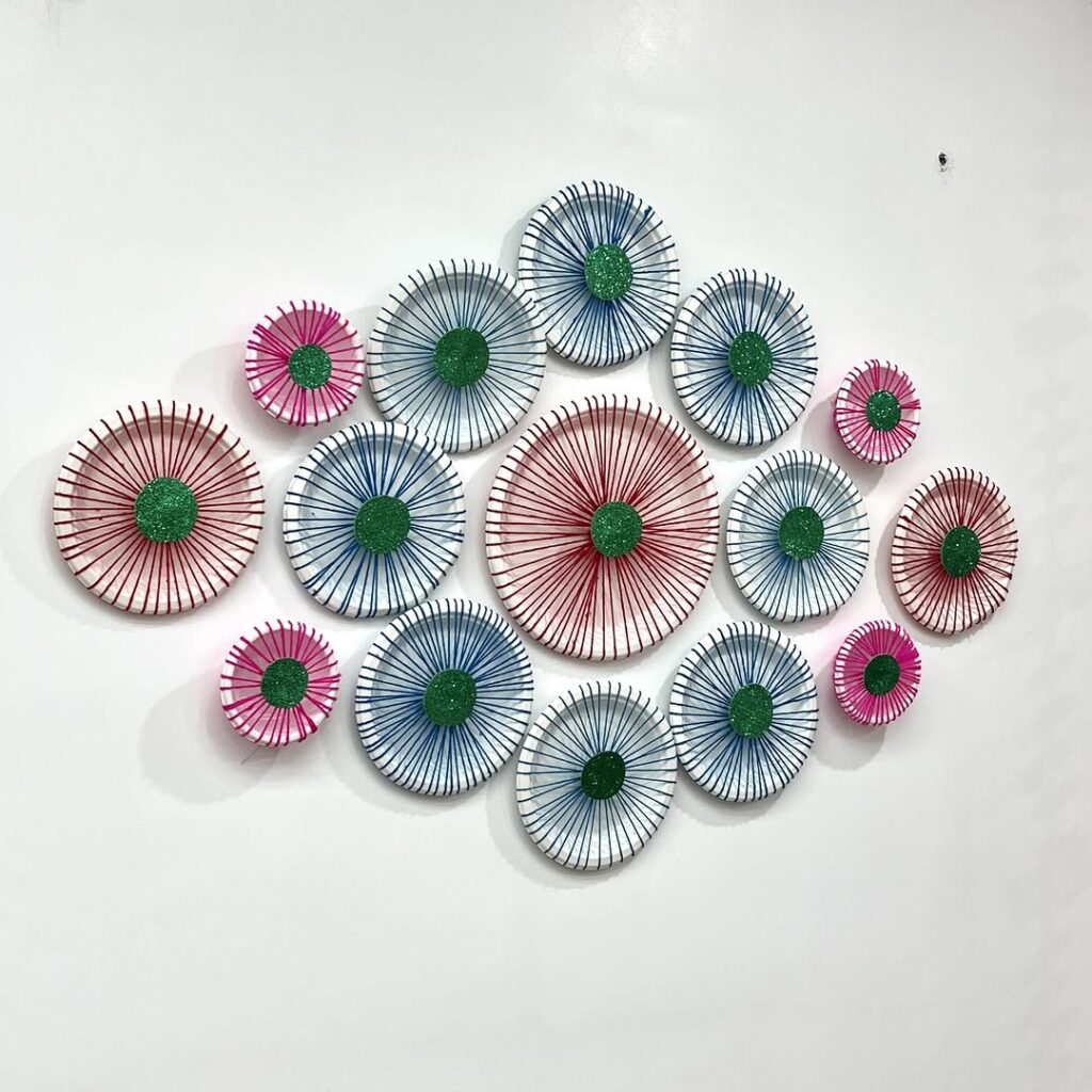 Paper pinwheel wall art arrangement in pink and blue with green centers