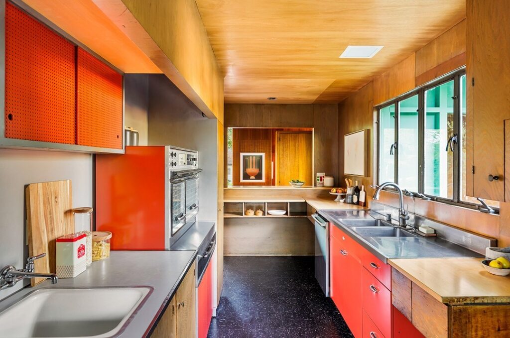 Vintage kitchen with coral cabinets and wood paneled walls