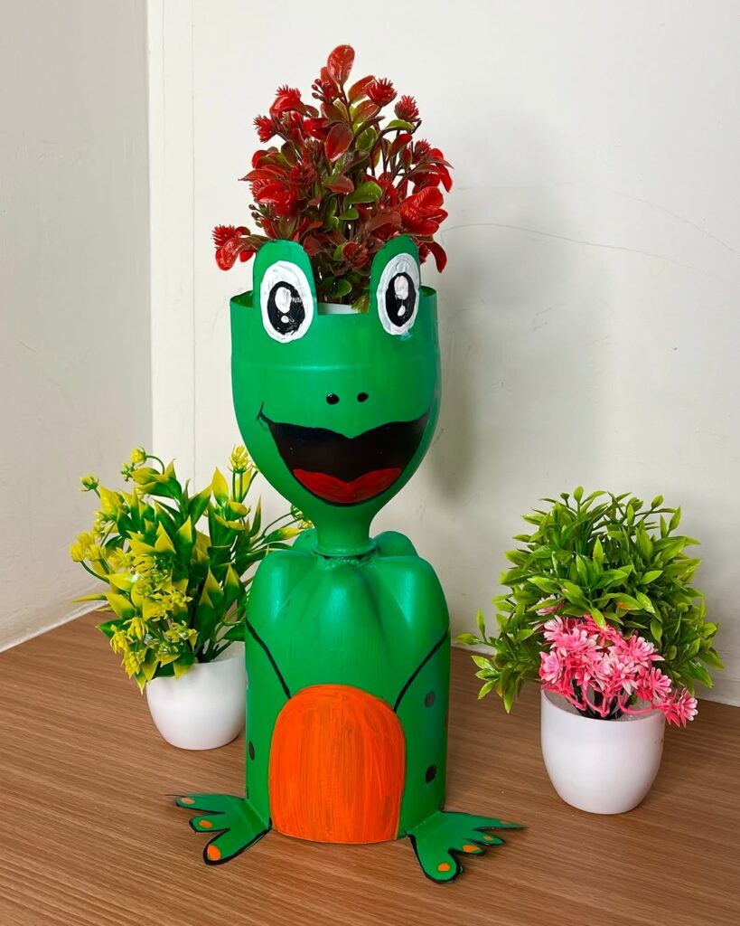 Green frog shaped planter with red flowers and decorative accents