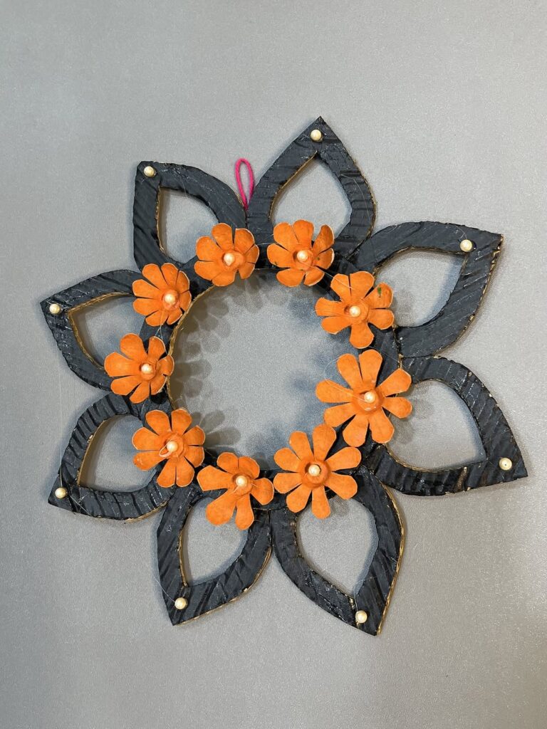 Black geometric wreath with orange paper flowers and pearl centers