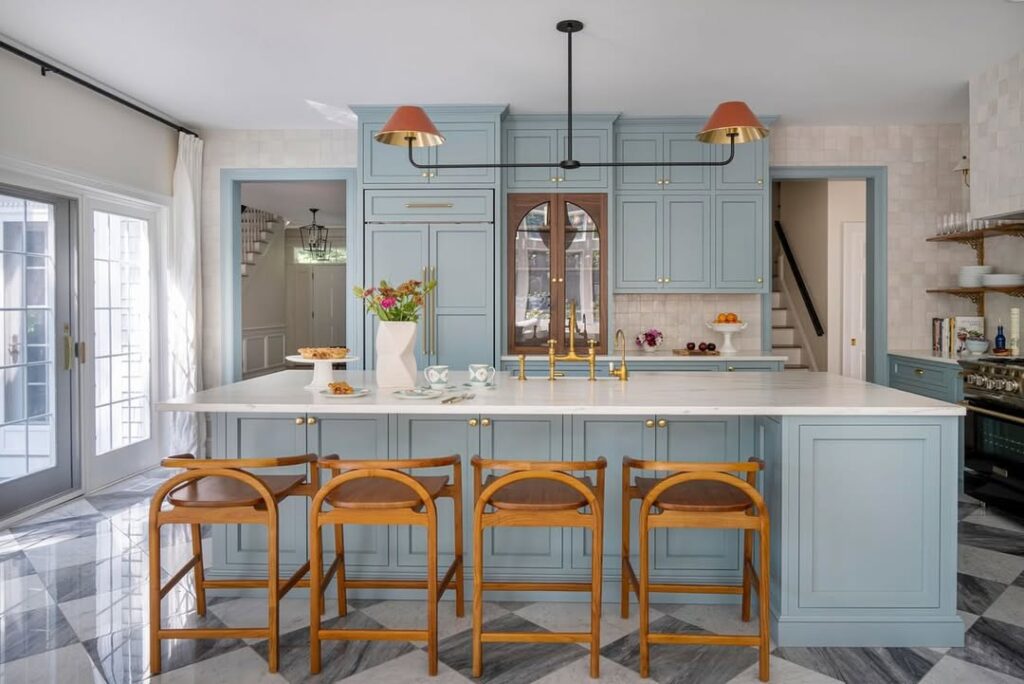 Light blue kitchen with coral pendants wooden stools and marble floors