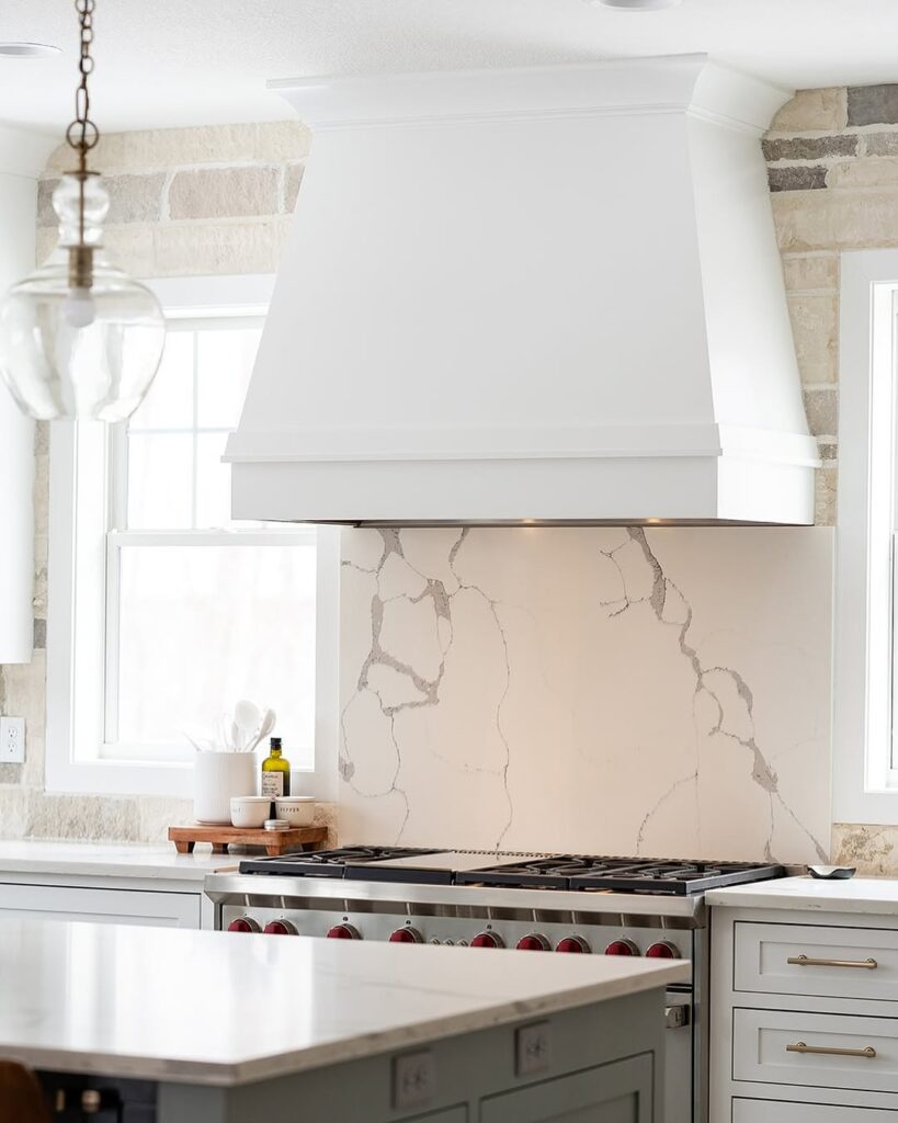 White kitchen with marble backsplash stone walls and brass accents