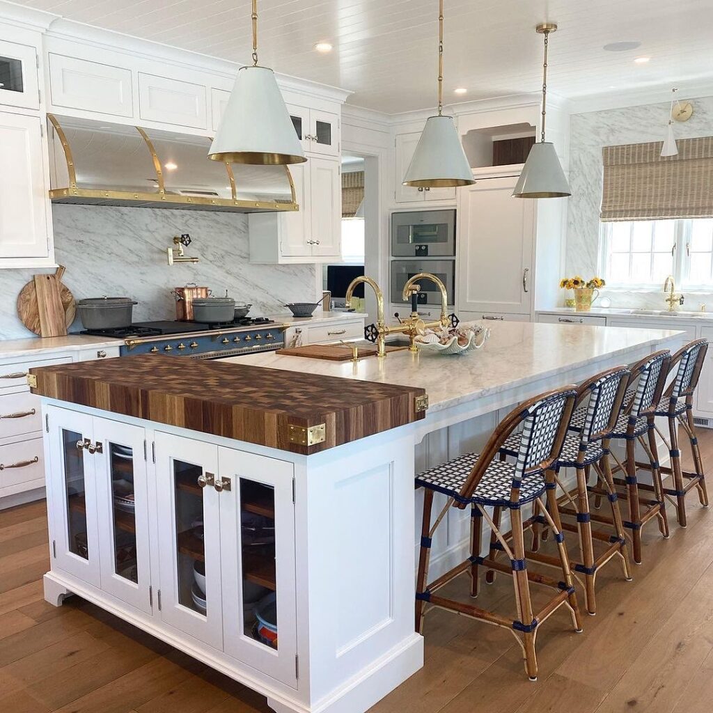 White kitchen with wooden butcher block island and bistro chairs