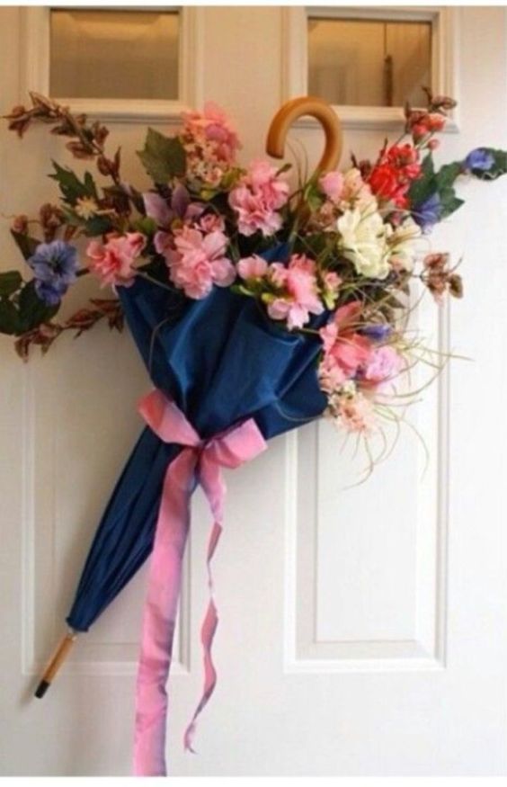 Navy umbrella filled with pink flowers hanging on white door