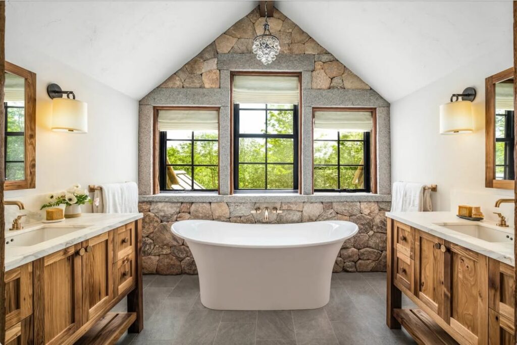 Lodge bathroom with stone walls and wooden vanities featuring modern tub