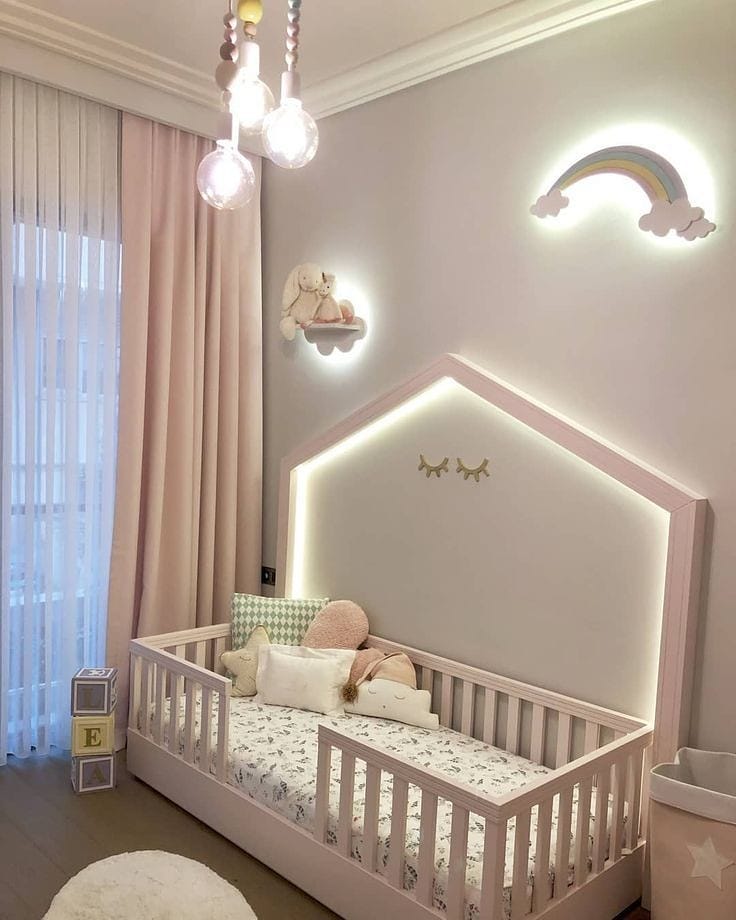 Pink nursery with house shaped crib illuminated cloud decorations and modern pendant lights