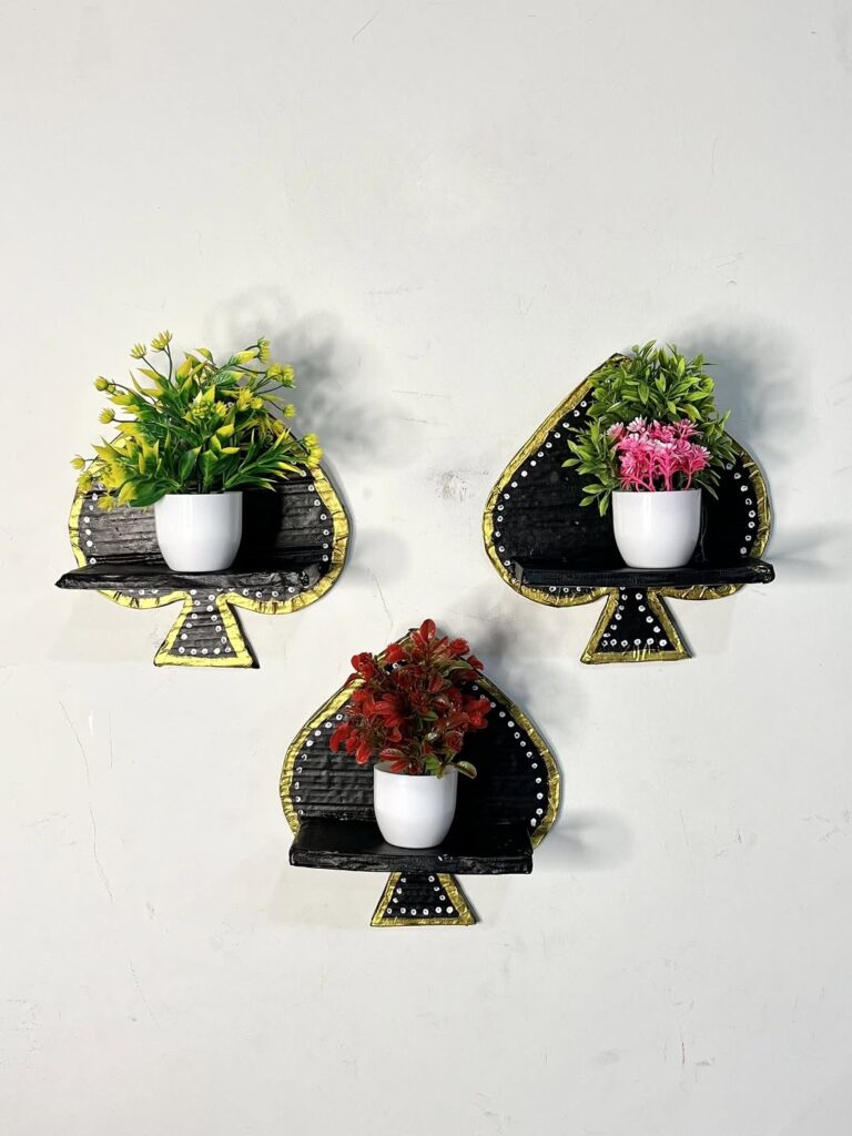 Three spade shaped wall shelves with potted plants in black and gold finish