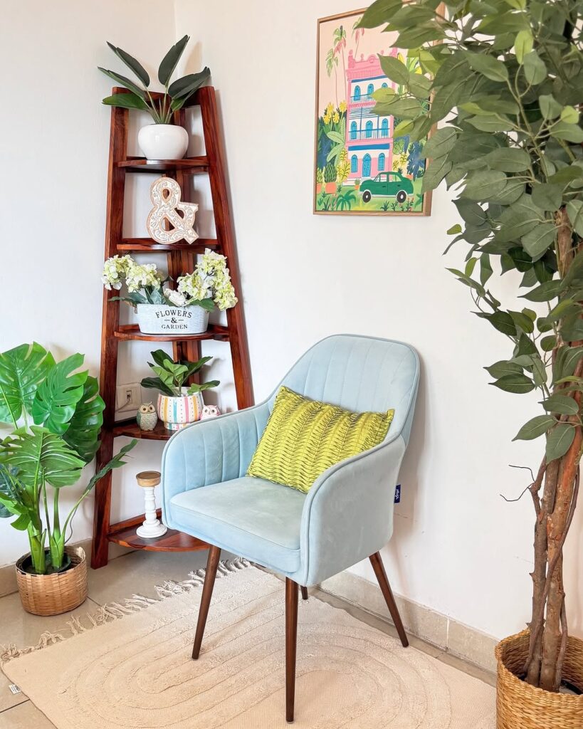  Light blue velvet chair with wooden ladder shelf and tropical wall art