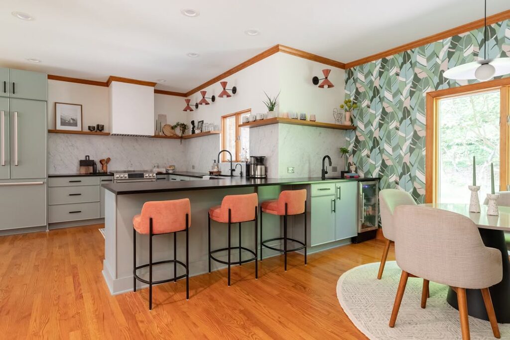 Kitchen with sage cabinets coral stools and leaf wallpaper