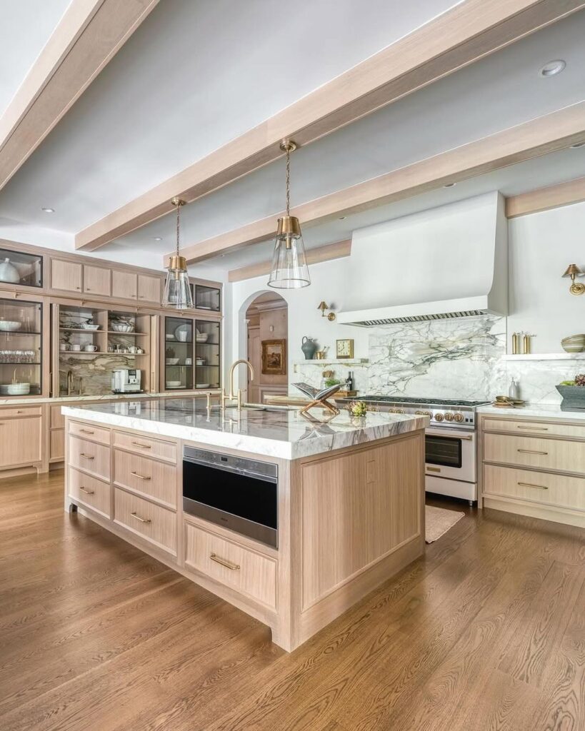 Kitchen with bleached oak cabinets marble counters and glass pendants