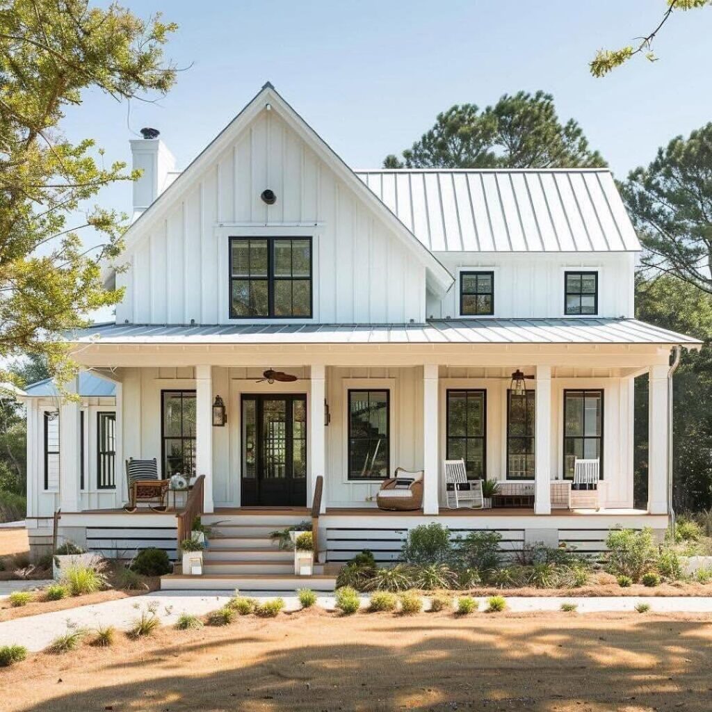 White farmhouse with wraparound porch black windows and coastal landscaping