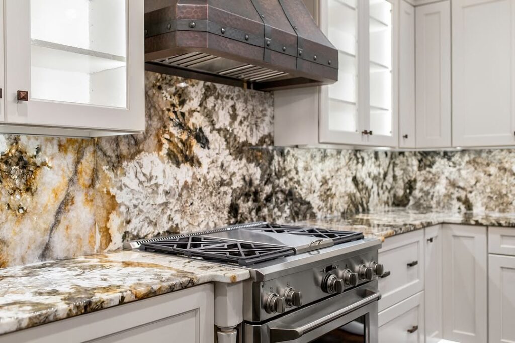  White kitchen with dramatic granite backsplash and copper hood