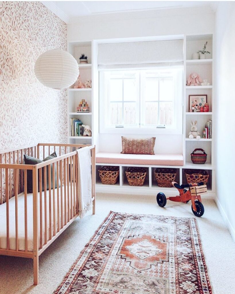 Natural wood nursery with window seat built in shelving and vintage Persian rug