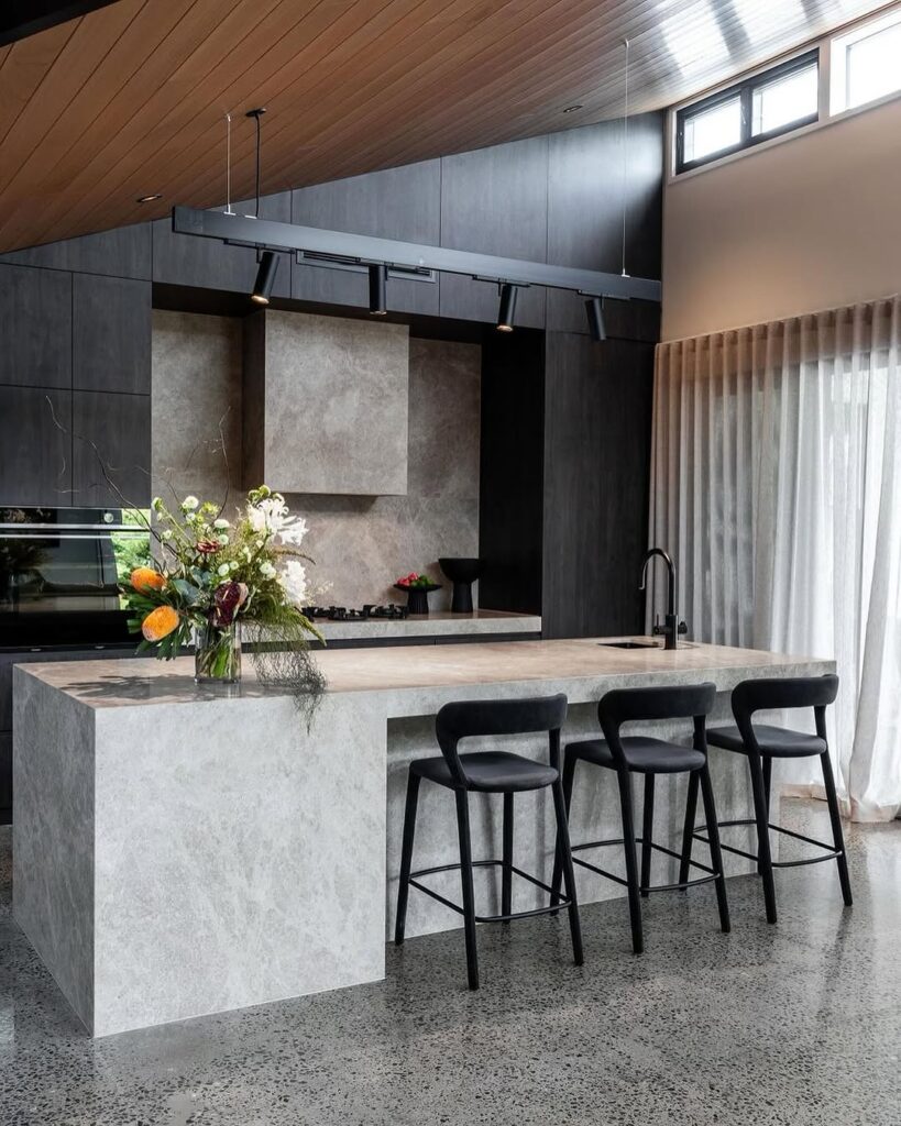 Modern kitchen with wooden ceiling dark cabinets and concrete island