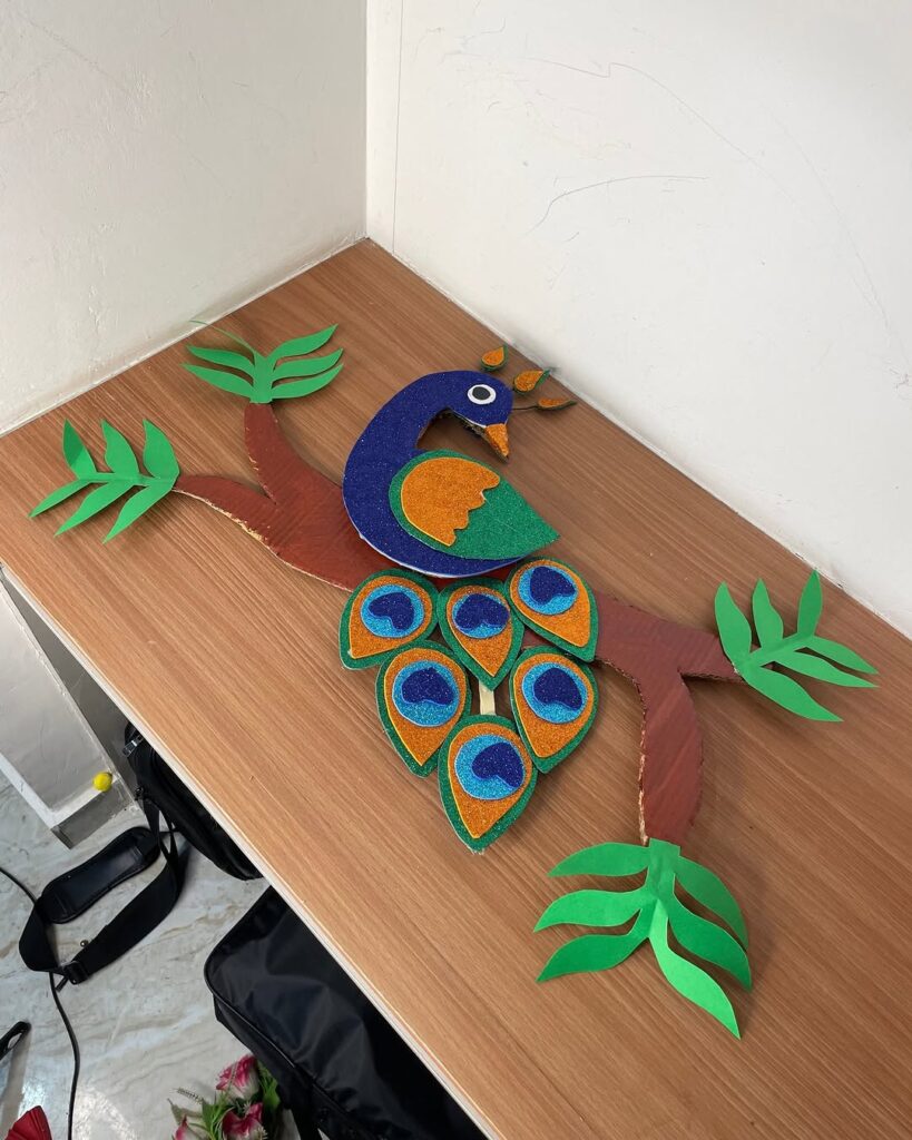 Paper peacock wall art with glitter accents and bamboo branch