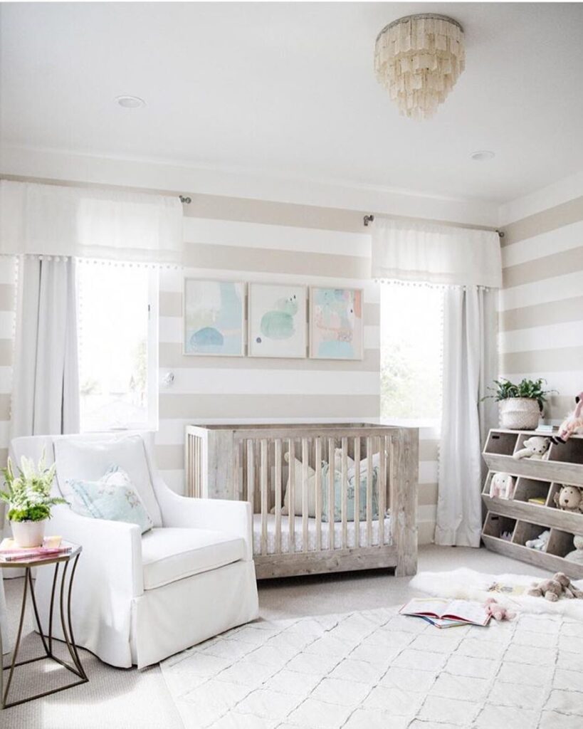 Striped wall nursery with driftwood crib white furniture and coastal artwork