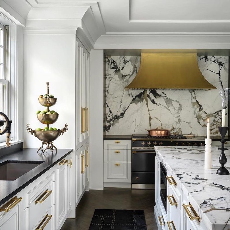 White kitchen with gold hood and dramatic marble backsplash