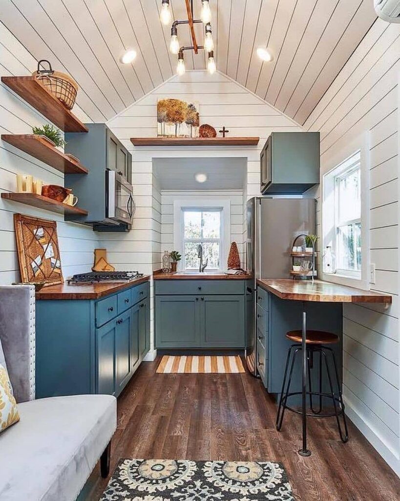 Teal kitchen cabinets with wooden countertops and white shiplap walls