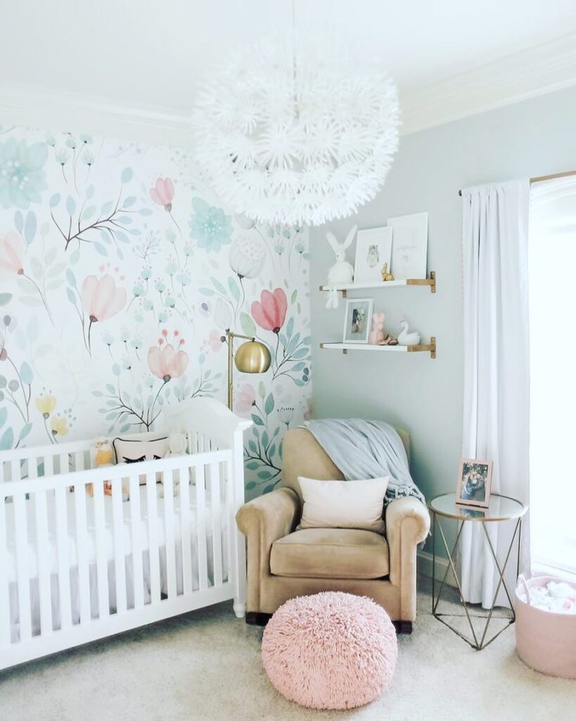 Nursery with floral wallpaper white crib and brass accents plus pink pouf