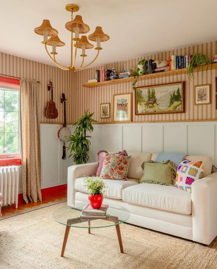 White sofa with woven chandelier striped wallpaper and cottage artwork