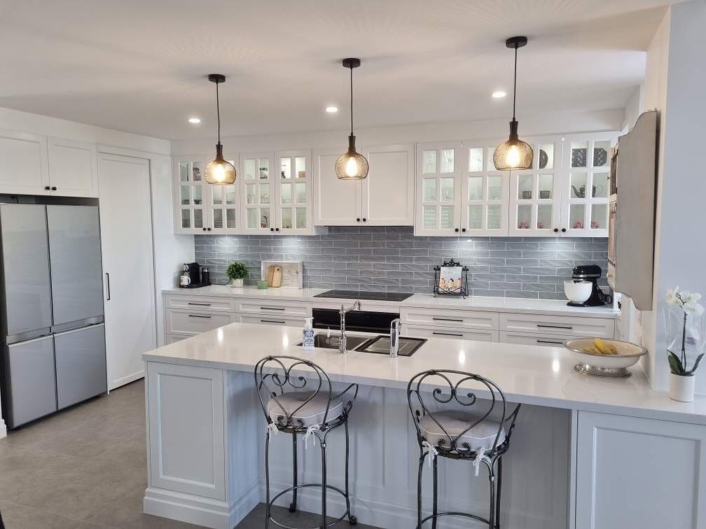  White kitchen with grey tile backsplash and glass pendant lights